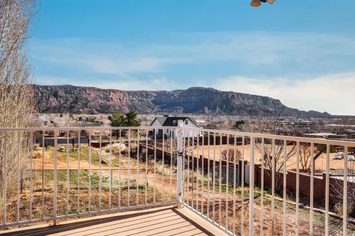 Expansive outdoor deck with a white metal railing, featuring a scenic mountainous backdrop