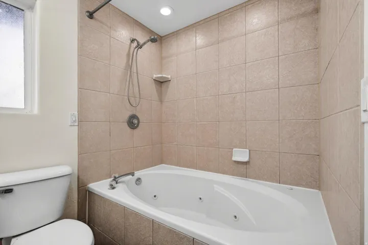 Jetted soaking tub with a tiled surround, complete with an integrated shower fixture