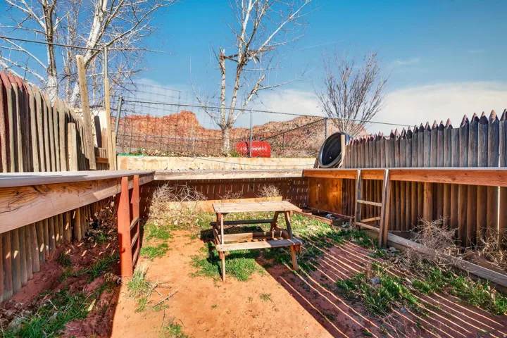 Private fenced yard with natural landscaping and red rock formations in the background