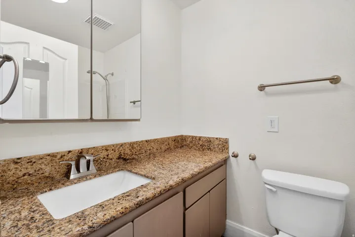 Bathroom vanity with a granite-style countertop, undermount sink, and brushed nickel faucet