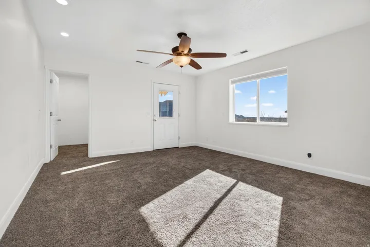 Carpeted room featuring a ceiling fan, recessed lighting, a large window, and a glass-paneled door