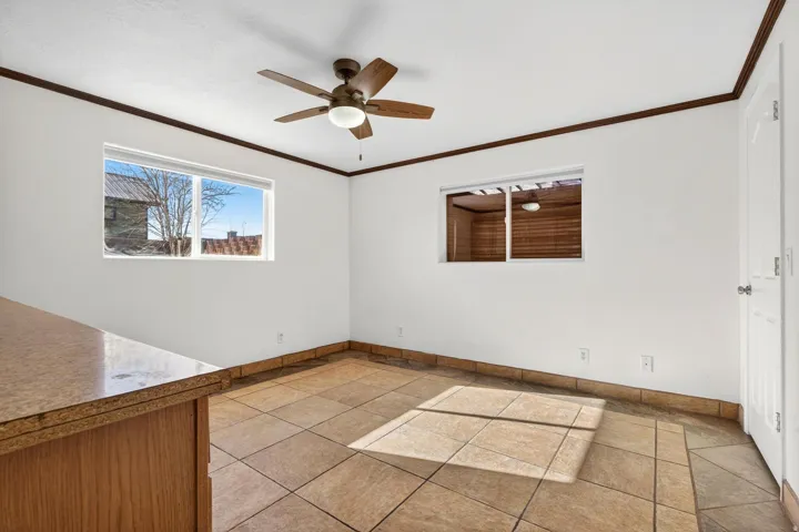 Room featuring light-toned tile flooring, white walls, and dark wood-finish trim