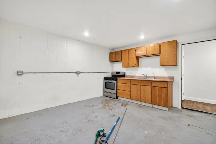 Compact kitchen area featuring wood-finish cabinetry, a stainless steel gas range, and a single basin sink