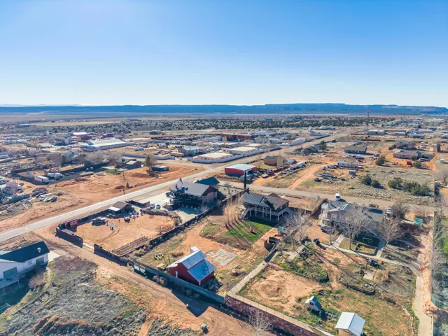 Aerial view showcasing multiple residential properties, expansive land, and distant mesa formations