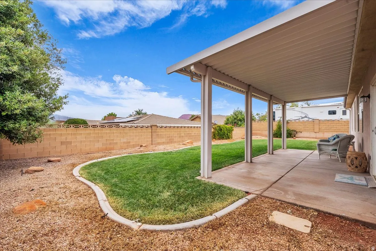 Extended covered patio with concrete flooring, bordered by a manicured lawn and gravel landscaping
