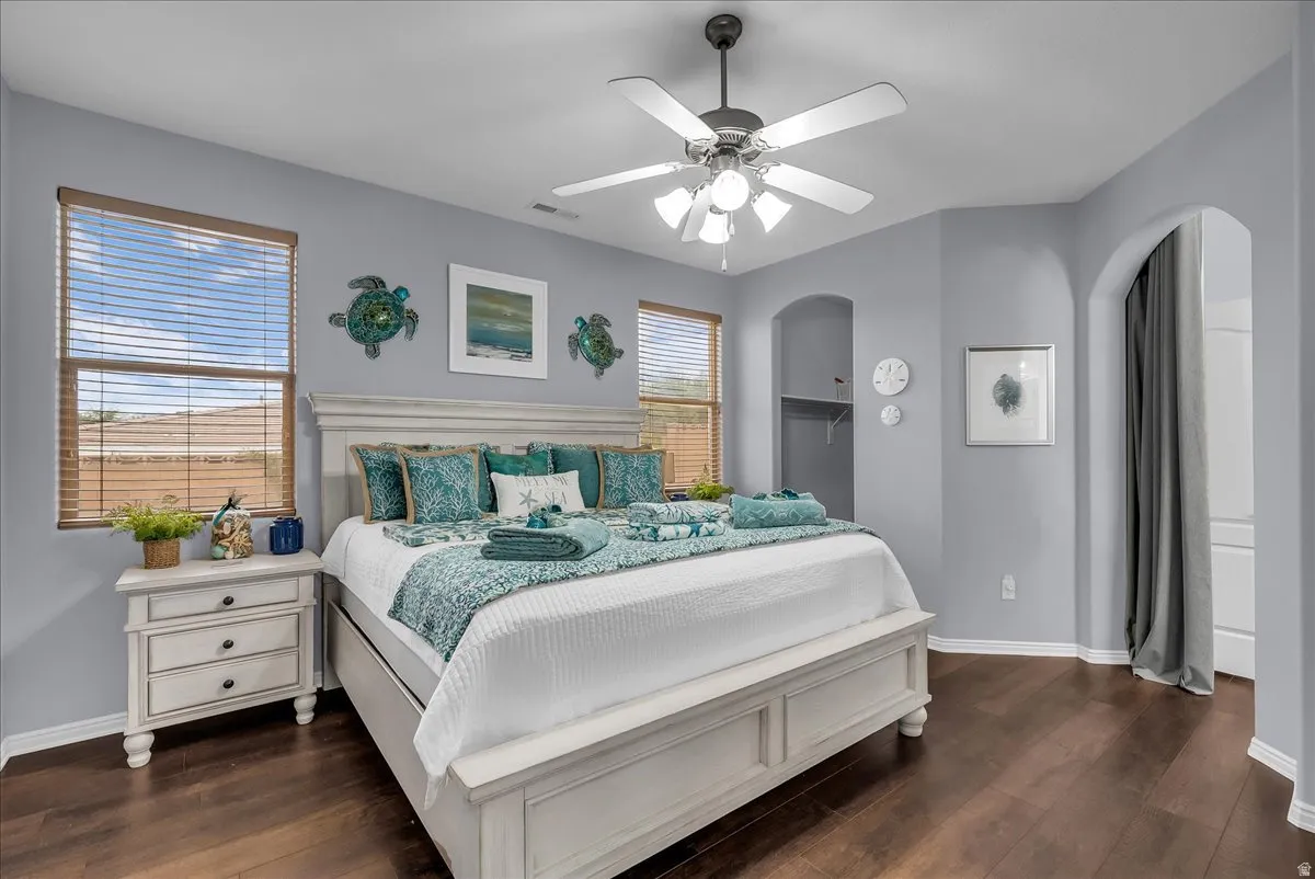 Spacious room featuring wood-finish flooring, a ceiling fan with light, and two windows with blinds