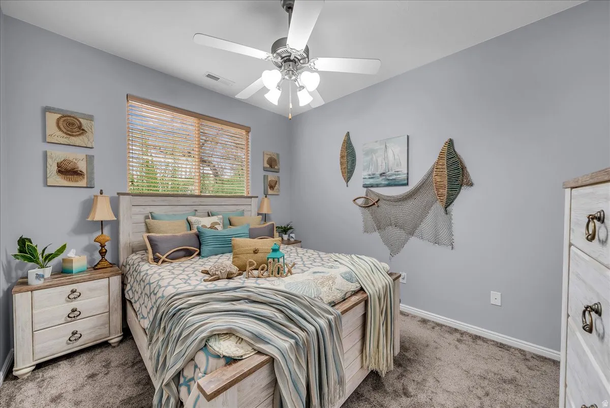 Bedroom featuring a ceiling fan with integrated lighting, a window with wood blinds, and carpeting