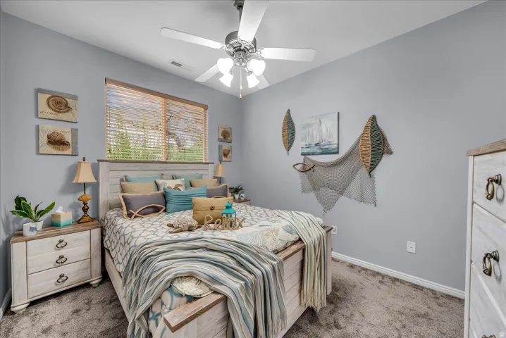 Bedroom featuring a ceiling fan with integrated lighting, a window with wood blinds, and carpeting