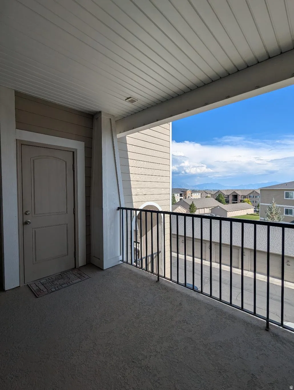Covered balcony with textured flooring and black metal railings