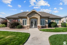 Stucco exterior featuring stone accents, a gabled entry, concrete walkways, and mature landscaping