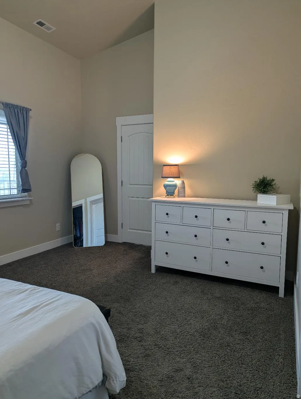 Carpeted room featuring a window with blinds, a white paneled door, and neutral-toned walls
