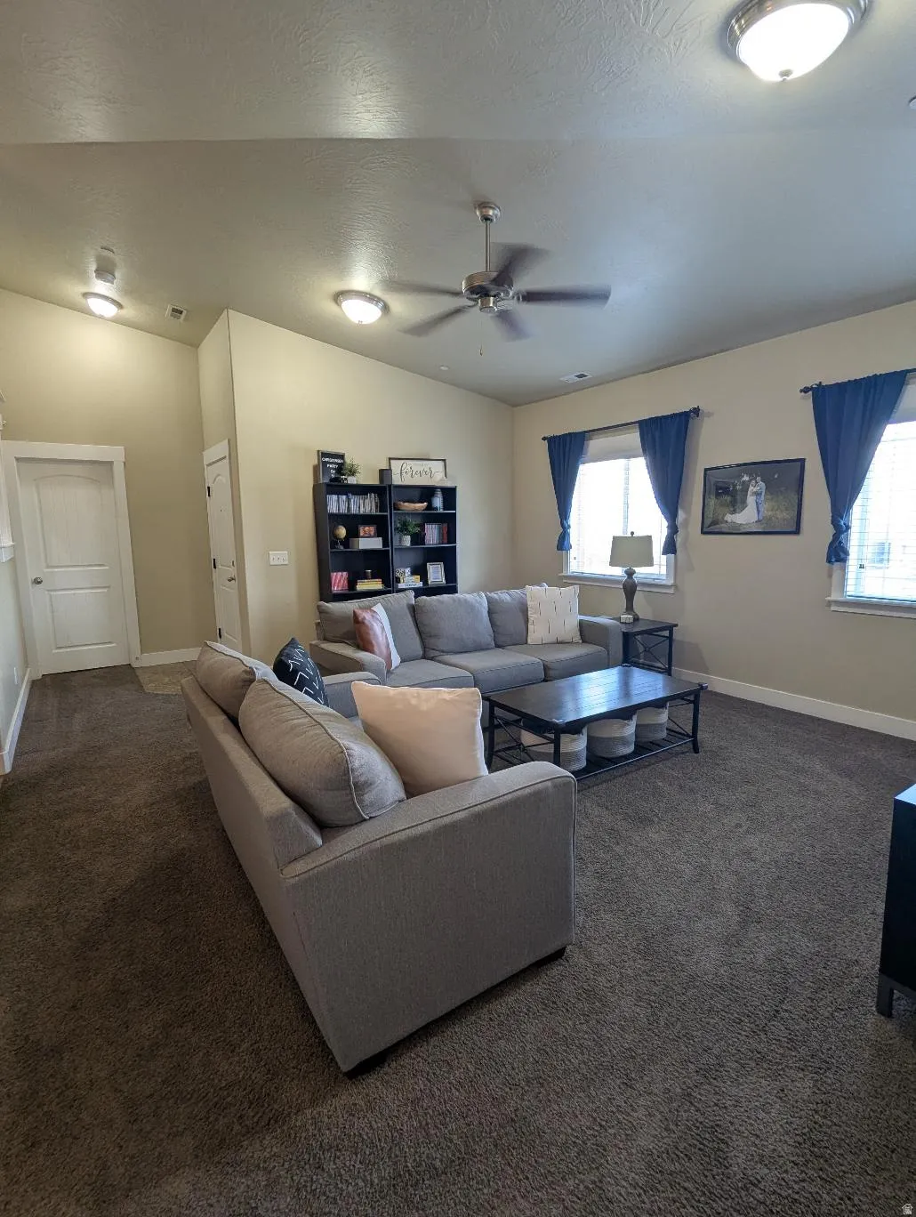 Spacious living area featuring neutral carpeting, a vaulted ceiling, and recessed lighting