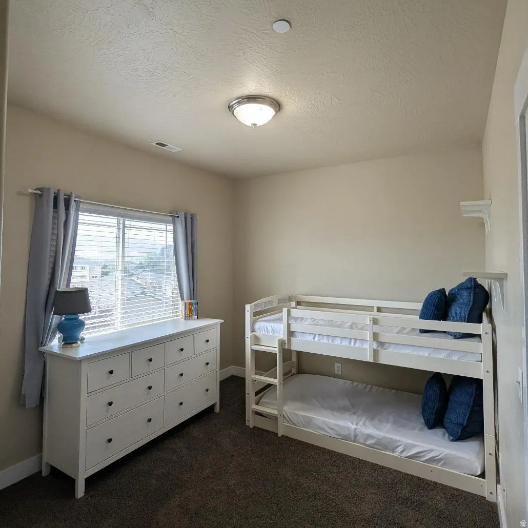 Carpeted room with a ceiling-mounted light fixture, neutral wall colors, and a window with blinds