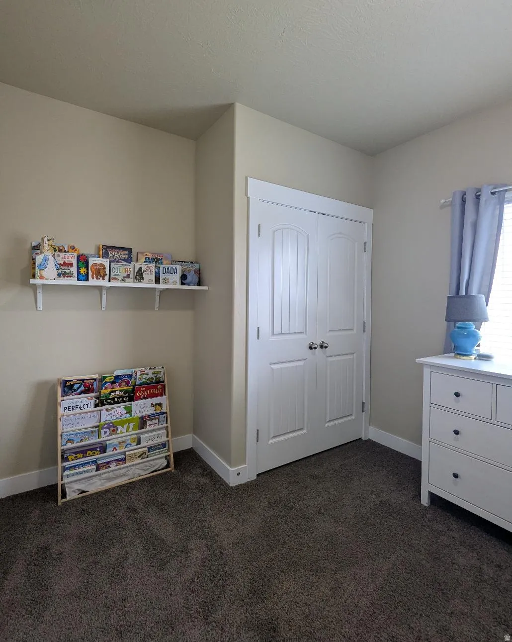Plush gray carpeting grounds this room, featuring light tan walls and white trim