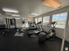 Fitness center featuring rubber flooring, multiple windows with horizontal blinds, and overhead fluorescent lighting