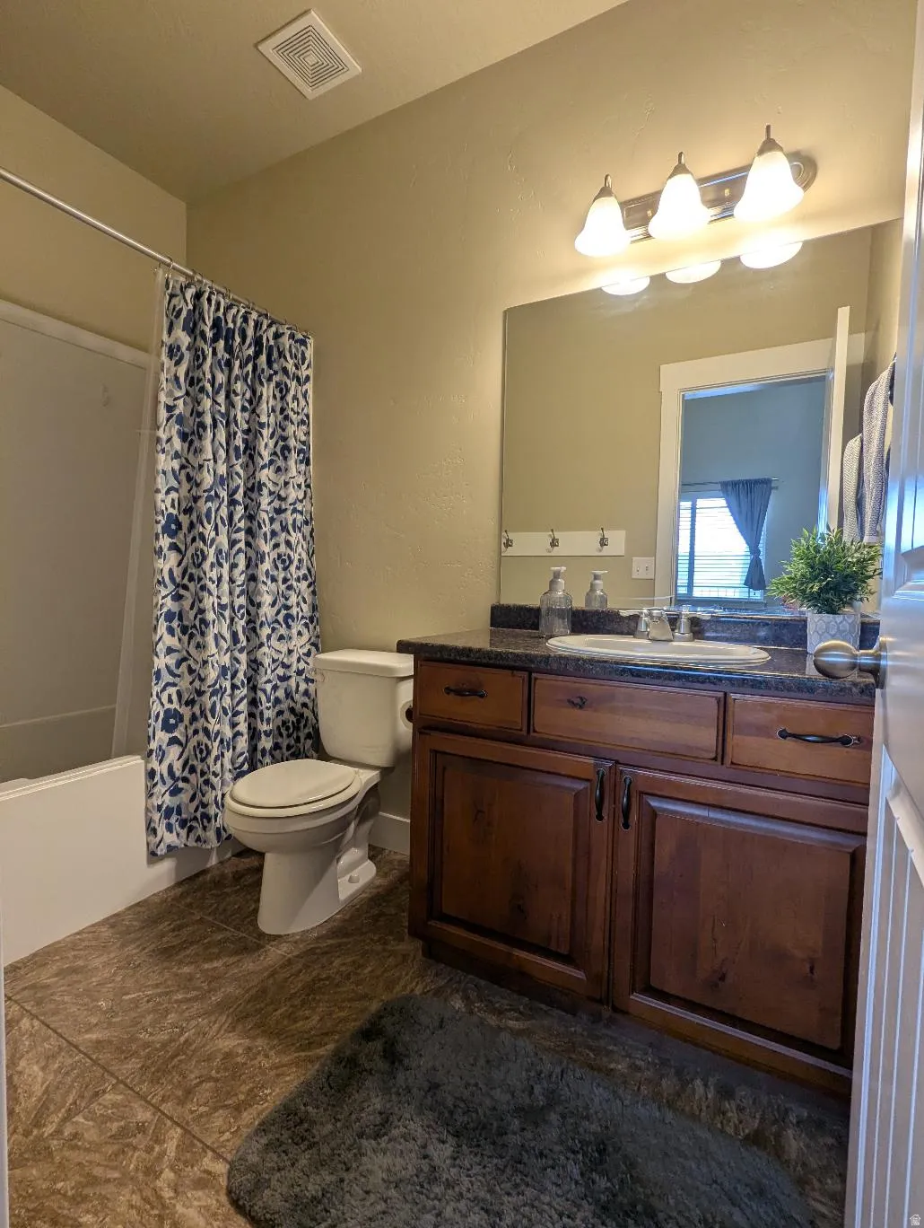 Full bathroom featuring a single vanity with wood cabinetry, dark countertop, and an integrated sink
