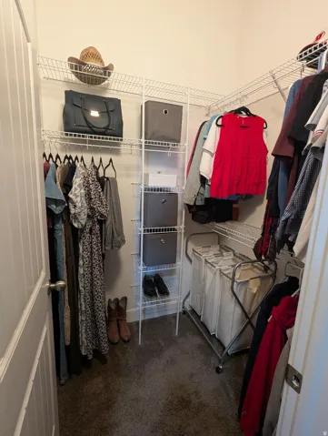 Walk-in closet featuring carpet flooring, white wire shelving, and multiple hanging rods for organization