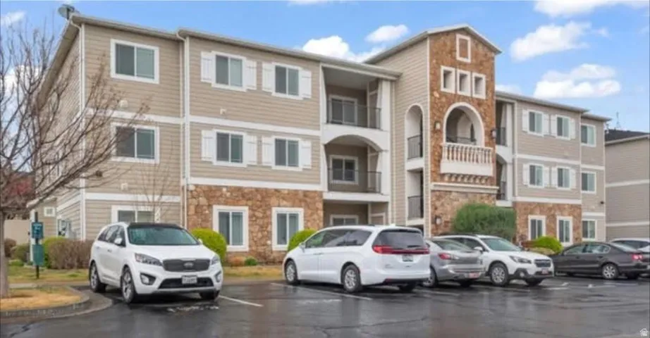 Multi-story residential building featuring neutral-toned siding, white-framed windows, and decorative white shutters