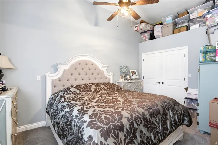 Vaulted ceiling bedroom featuring light-colored walls, a ceiling fan with integrated lighting, and a double-door closet with black hardware