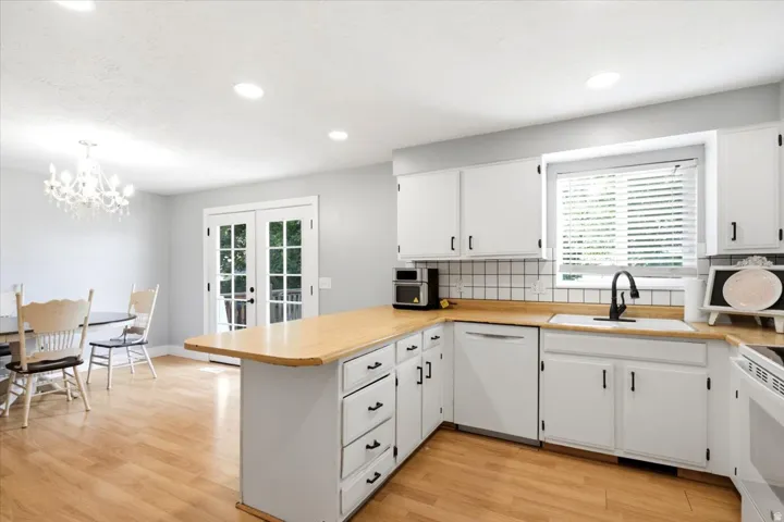 Kitchen featuring white cabinetry with dark hardware, wood-finish countertops, and a white subway tile backsplash