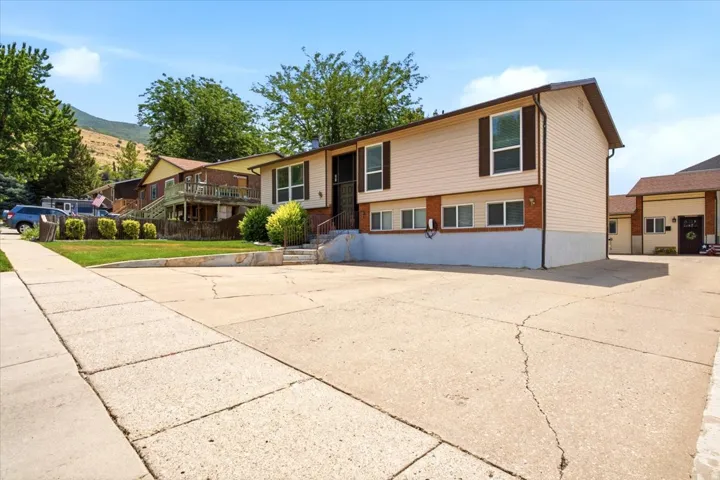 Split-level residence featuring light-toned siding, brown brick accents, and a blue-painted lower foundation