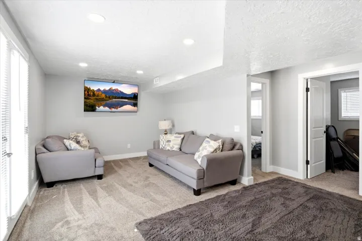 Recessed lighting illuminates this space featuring light gray walls, textured white ceilings, and gray patterned carpeting