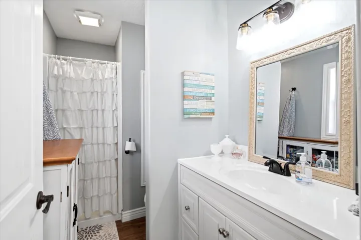 Bathroom featuring a white vanity with an integrated sink, dark bronze faucet, and an ornate framed mirror