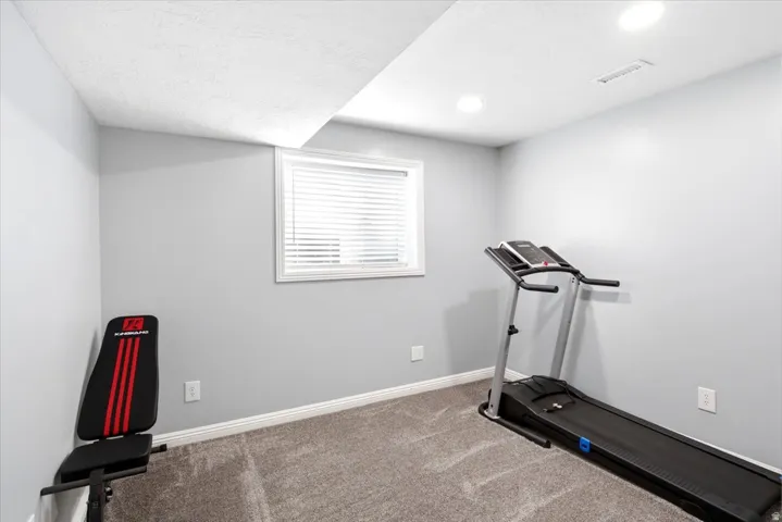Versatile room featuring light gray walls, gray carpet flooring, and a single window with white blinds