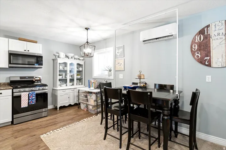 Kitchen and dining area featuring wood-finish flooring, white cabinetry, stainless steel appliances, and a built-in wall unit