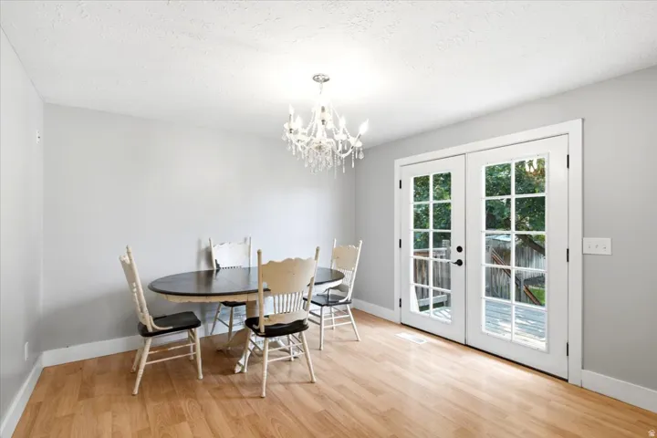 Double French doors with divided lites, crystal chandelier, light wood-finish flooring, and light gray walls