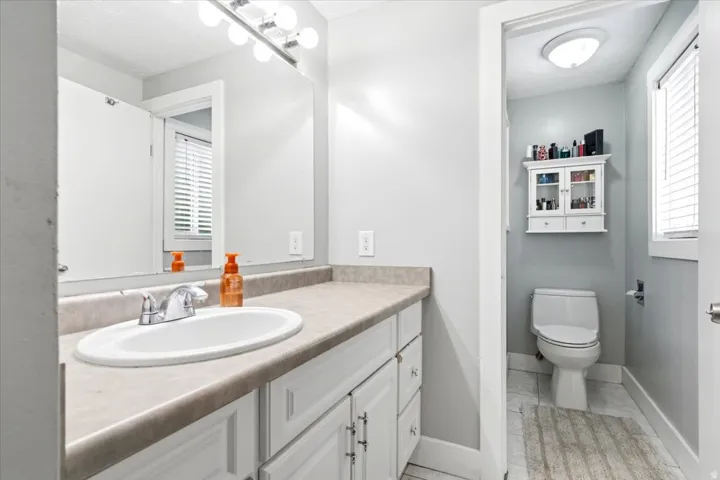 Vanity with an integrated oval sink, chrome faucet, and expansive mirror