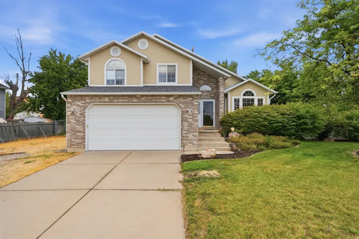 Two-story residence featuring a brick and stucco exterior, an attached two-car garage, and a concrete driveway