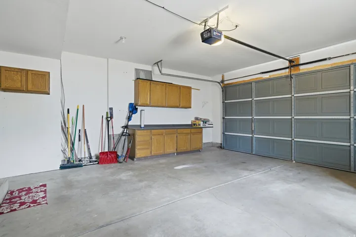 Two-car garage featuring a concrete floor, two paneled garage doors, built-in cabinetry, and overhead lighting