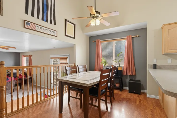 Dining area featuring wood-finish flooring, a ceiling fan, and a window with blinds