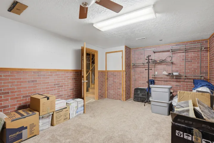 Spacious room featuring brick-patterned wainscoting, light carpeting, and a ceiling fan