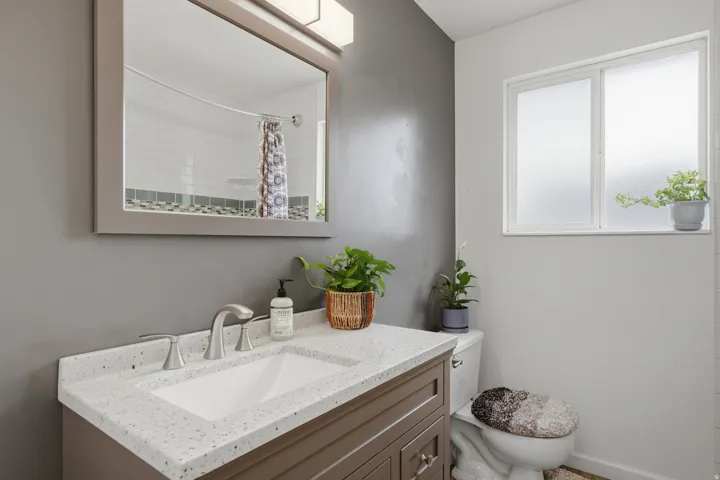 Vanity featuring a light speckled countertop, undermount sink, and brushed nickel faucet