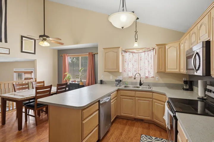 Open-concept kitchen featuring light wood cabinetry, stainless steel appliances, and a peninsula countertop