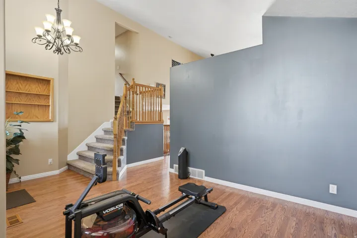 Foyer featuring vaulted ceilings, wood-finish flooring, a grand staircase with carpeted treads and wood railings, and a built-in wall niche