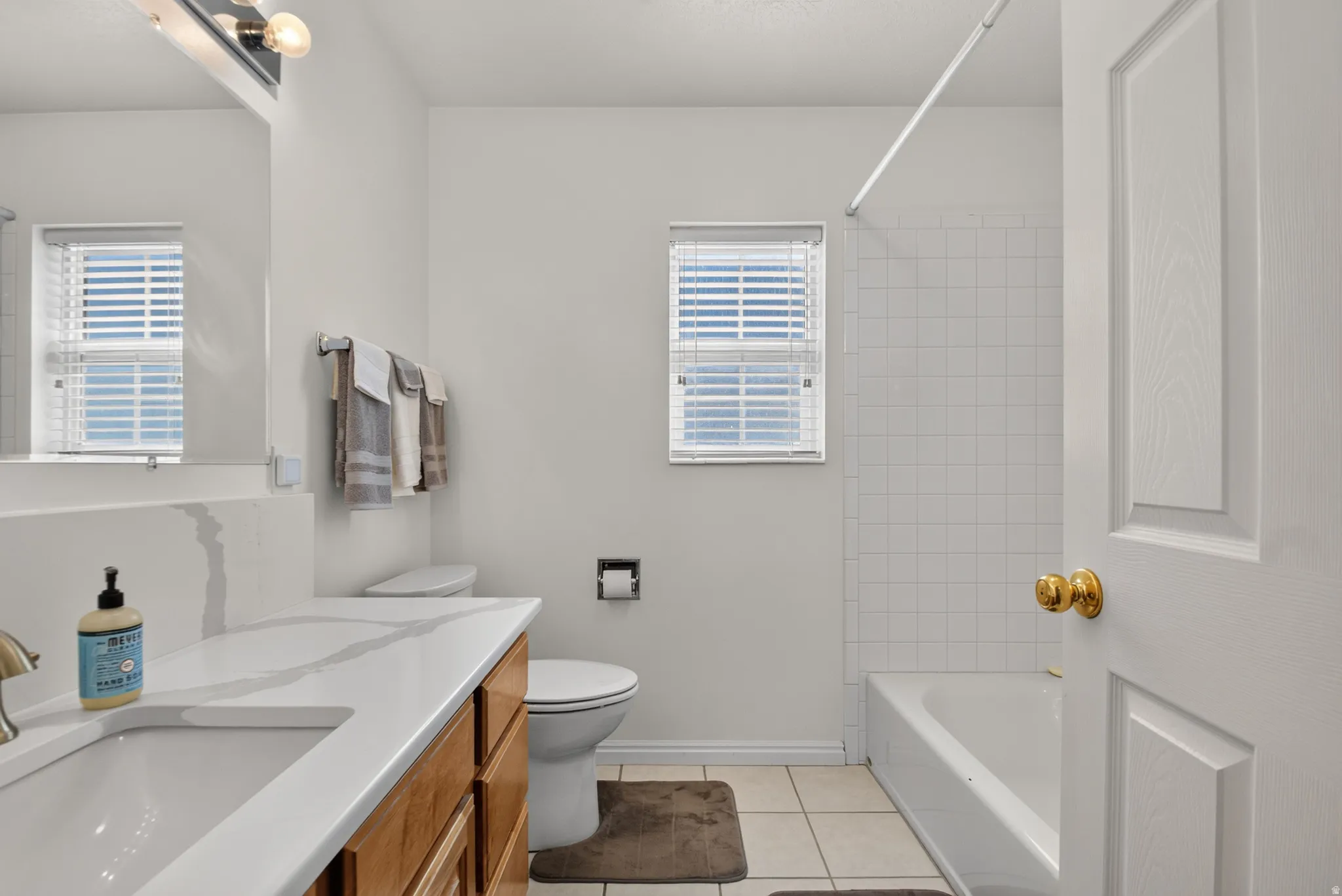 Bathroom vanity featuring a single basin sink, white countertop, and wood-finish cabinetry