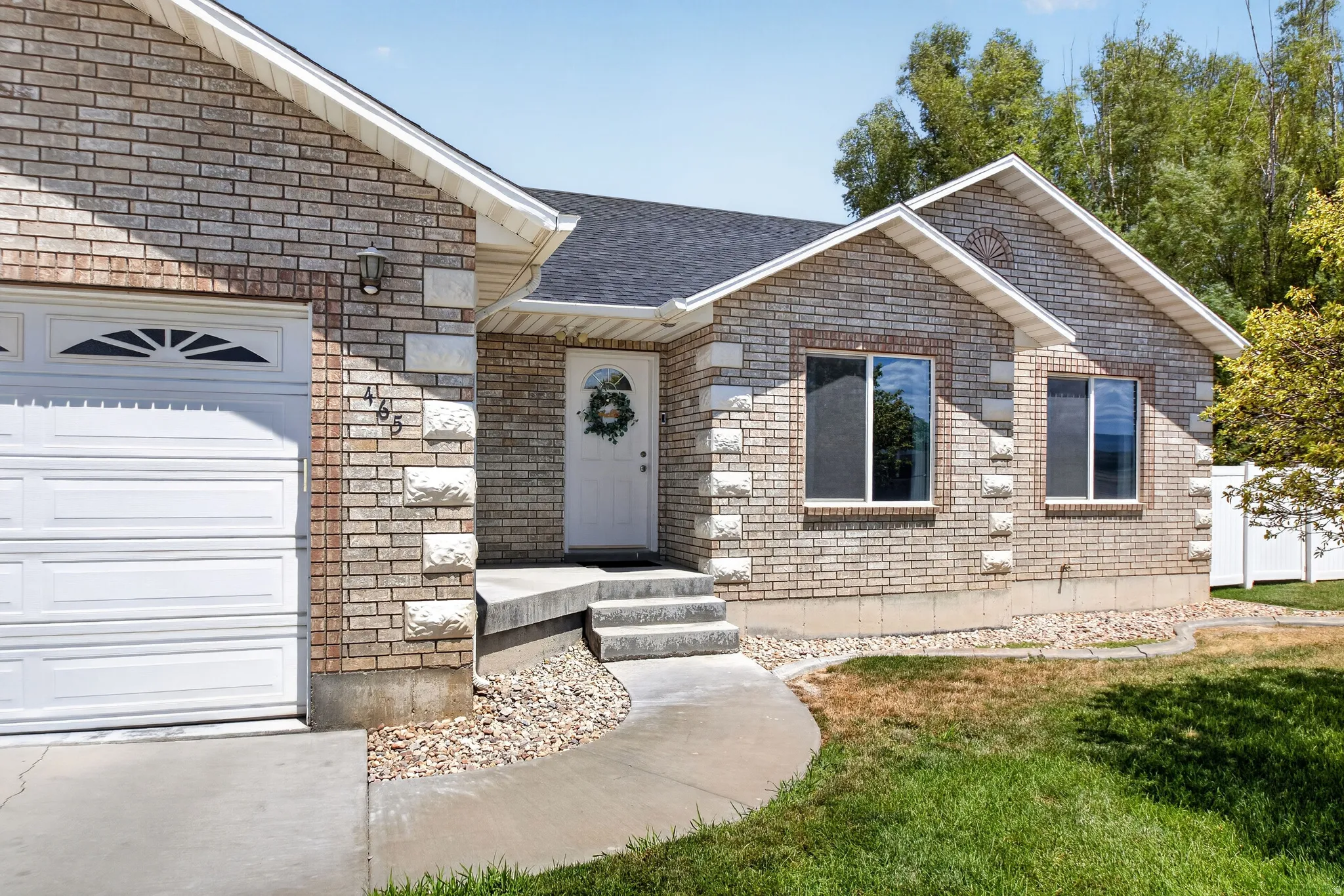 Brick facade residence featuring white trim, a black shingle roof, and an attached garage with a panel door