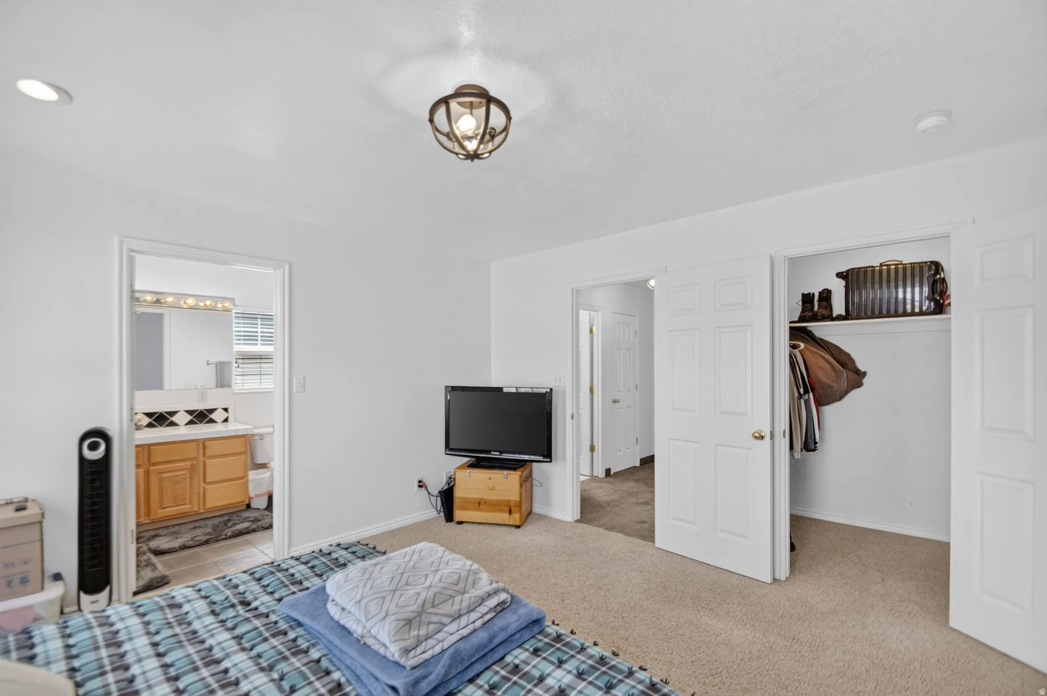 Bedroom featuring plush carpeting, a built-in closet with bi-fold doors, and a decorative ceiling light fixture