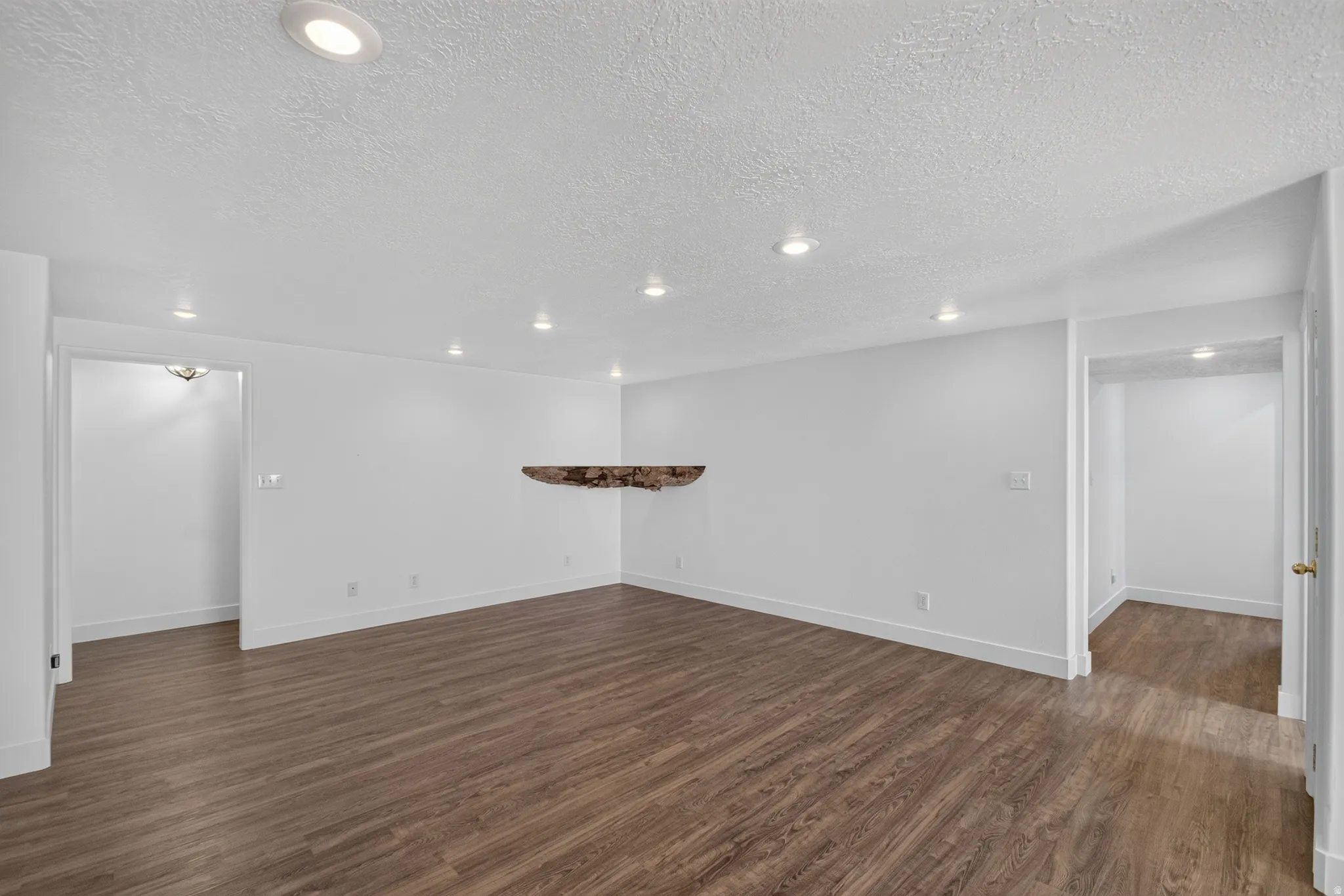 Spacious room featuring wood-finish flooring, white walls, and recessed lighting