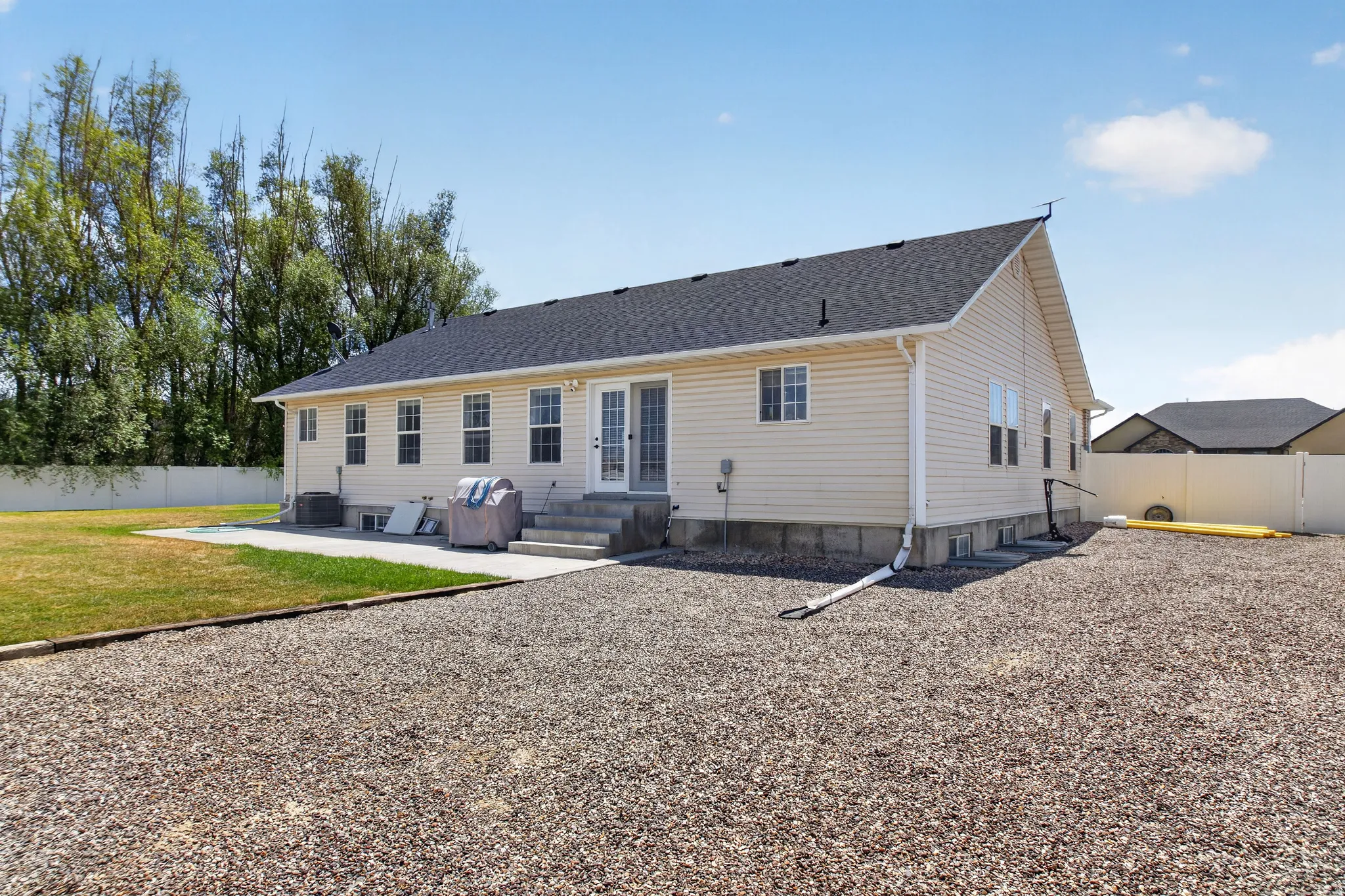 Rear exterior featuring light-toned siding, a dark shingle roof, and multiple windows