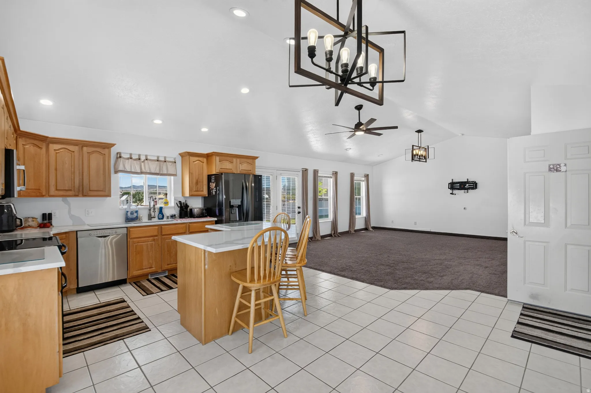 Open-concept kitchen featuring light wood cabinetry, stainless steel appliances, and a central island with countertop seating
