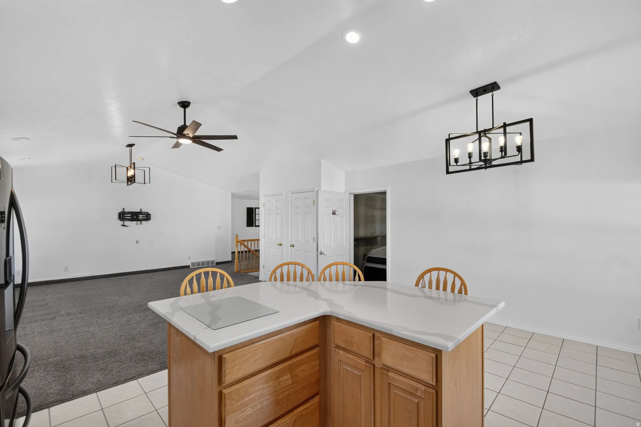 Kitchen island with light wood cabinetry, a white countertop, and tile flooring