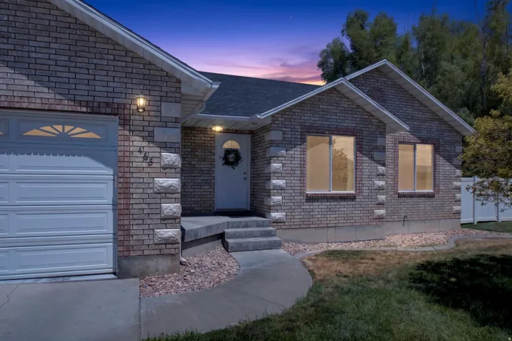 Brick and stone exterior featuring a covered entry, attached garage with decorative windows, and a paved walkway
