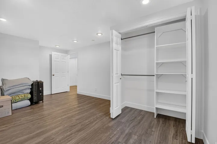 Spacious room featuring wood-finish flooring, recessed lighting, and white baseboards