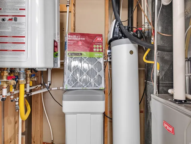Dedicated utility area featuring a tankless water heater, water softener system, water filtration system, and a Bryant furnace