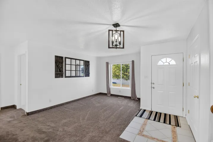 Bright entry space featuring a white paneled door with an arched window, tile flooring at the entrance, and dark wood-finish light fixture