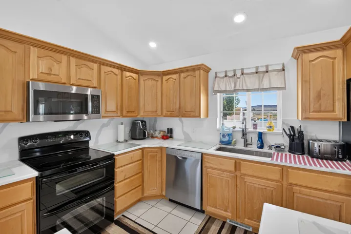 Kitchen featuring light wood cabinetry, white countertops with a patterned backsplash, and recessed lighting